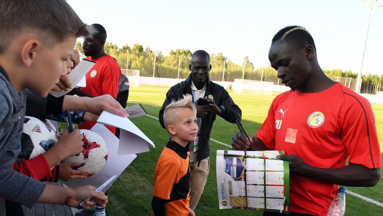 15 июня. Калуга. Нападающий сборной Сенегала Садио МАНЕ после тренировки подписывает журнал юному болельщику. Фото AFP 15 июня. Калуга. Нападающий сборной Сенегала Садио МАНЕ после тренировки подписывает журнал юному болельщику. Фото AFP