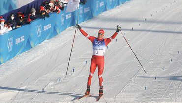 Александр Большунов с флагом на финише скиатлона.