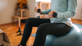 Девушка упражняется с гантелями.