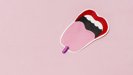 Противозачаточная таблетка на высунутом языке на розовом фоне