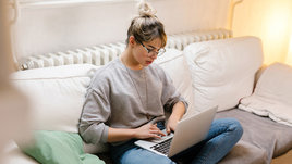 Девушка сидит за ноутбуком.