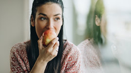 Девушка ест яблоко.