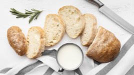 Нарезка из белого хлеба на столе с кружкой молока