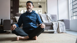 Мужчина медитирует сидя на полу.