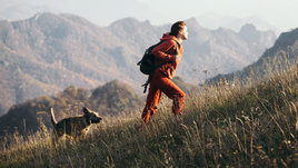 Девушка во время похода в горы с собакой