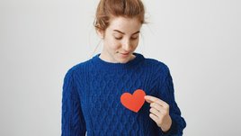 Девушка держит красное сердечко у груди