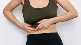 Девушка держится за больной живот.