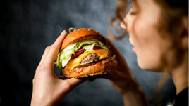 Девушка держит в руке бургер