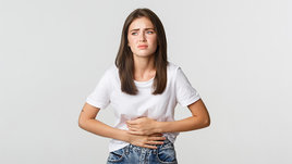 Девушка держится за больной живот.