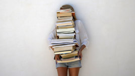 Девушка держит в руке стопку книг