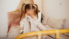 Плачущая маленькая девочка в постели.