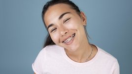 Молодая девушка с брекетами широко улыбается