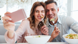 Пара ест салаты в ресторане и делает селфи