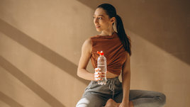 Красивая стройная девушка на тренировке с бутылкой воды