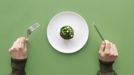 Полупустая тарелка на зеленом фоне, девушка держит вилку и нож