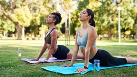 Две красивые молодые девушки занимаются йогой в парке