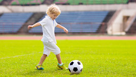 Мальчик играет с футбольным мячом на поле