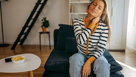 Девушка держится за шею, скорчившись от боли