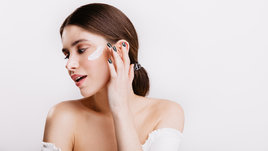 Красивая девушка наносит крем на лицо