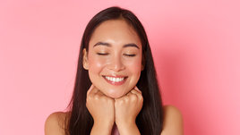 Девушка улыбается и держится за подбородок.