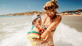 Молодая женщина купается в море с сыном