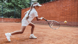 Девочка играет в теннис на корте