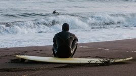 Мужчина в гидрокостюме занимается серфингом на Камчатке