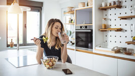 Девушка на кухне пьет из прозрачного стакана