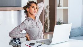 Девушка держится за спину и испытывает дискомфорт