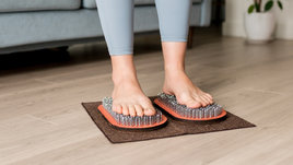 Девушка пробует стоять на гвоздях дома.