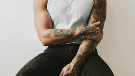 Молодой человек с татуировками на руках и груди