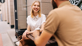 Счастливая молодая пара встречается вместе, сидя за столом в уличном кафе летним днем