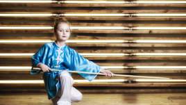 Красивая маленькая девочка в комнате в спортивной одежде для боевых искусств Ушу