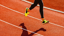 Спортсмен бежит по стадиону.