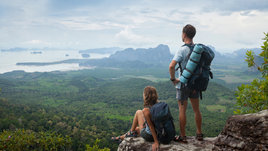 Девушка и парень стоят на вершине горы и смотрят на горизонт
