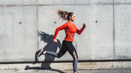 Девушка бежит на фоне стены.