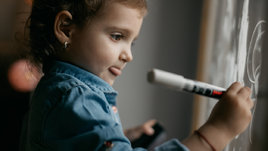 Маленькая девочка рисует на окне