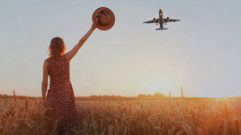 Девушка стоит в поле, а сверху самолет