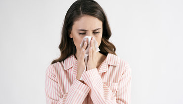 Женщина сморкается.