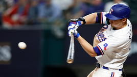 Бейсболист отбивает мяч битой.