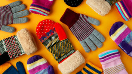 Различные перчатки и варежки на оранжевом фоне