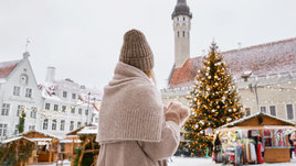 Девушка на улице перед елкой.