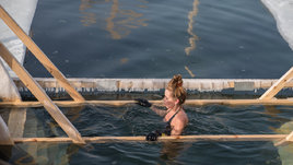 Девушка окунается в прорубь зимой на Крещение.
