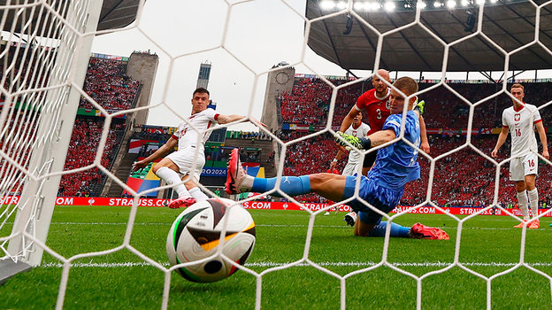 Кшиштоф Пентек (слева) отправляет мяч в ворота сборной Австрии.