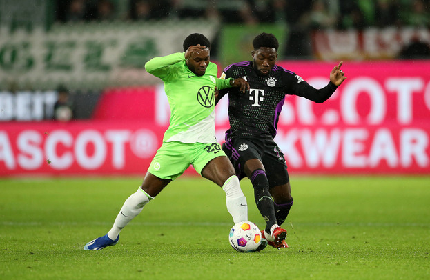 Альфонсо Дэвис (справа) борется за мяч с футболистом «Вольфсбурга» Ридли Баку.