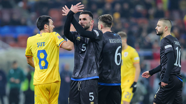 Защитник сборной Косово Люмбард Делова (в центре) показывает знак мира румынским болельщикам. Защитник сборной Косово Люмбард Делова (в центре) показывает знак мира румынским болельщикам.