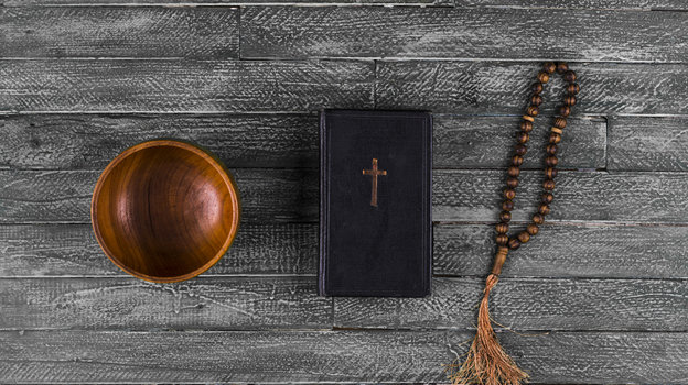 Библия и четки на старом деревянном столе