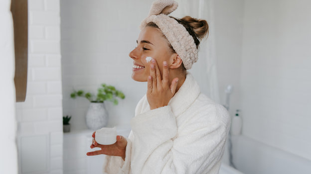 Девушка наносит крем на лицо