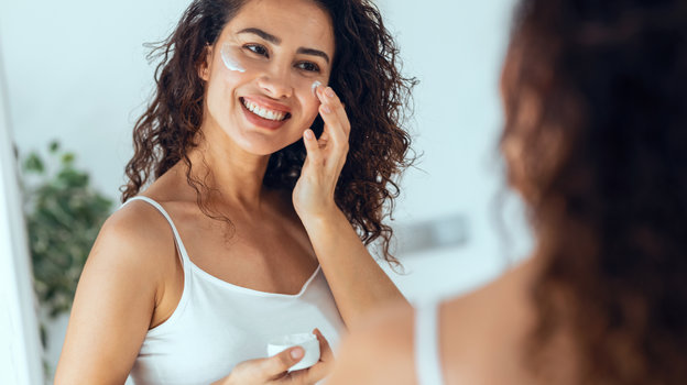 Девушка наносит крем на лицо