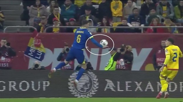 Мяч попадает в руку футболисту сборной Боснии Беньямину Тахировичу.